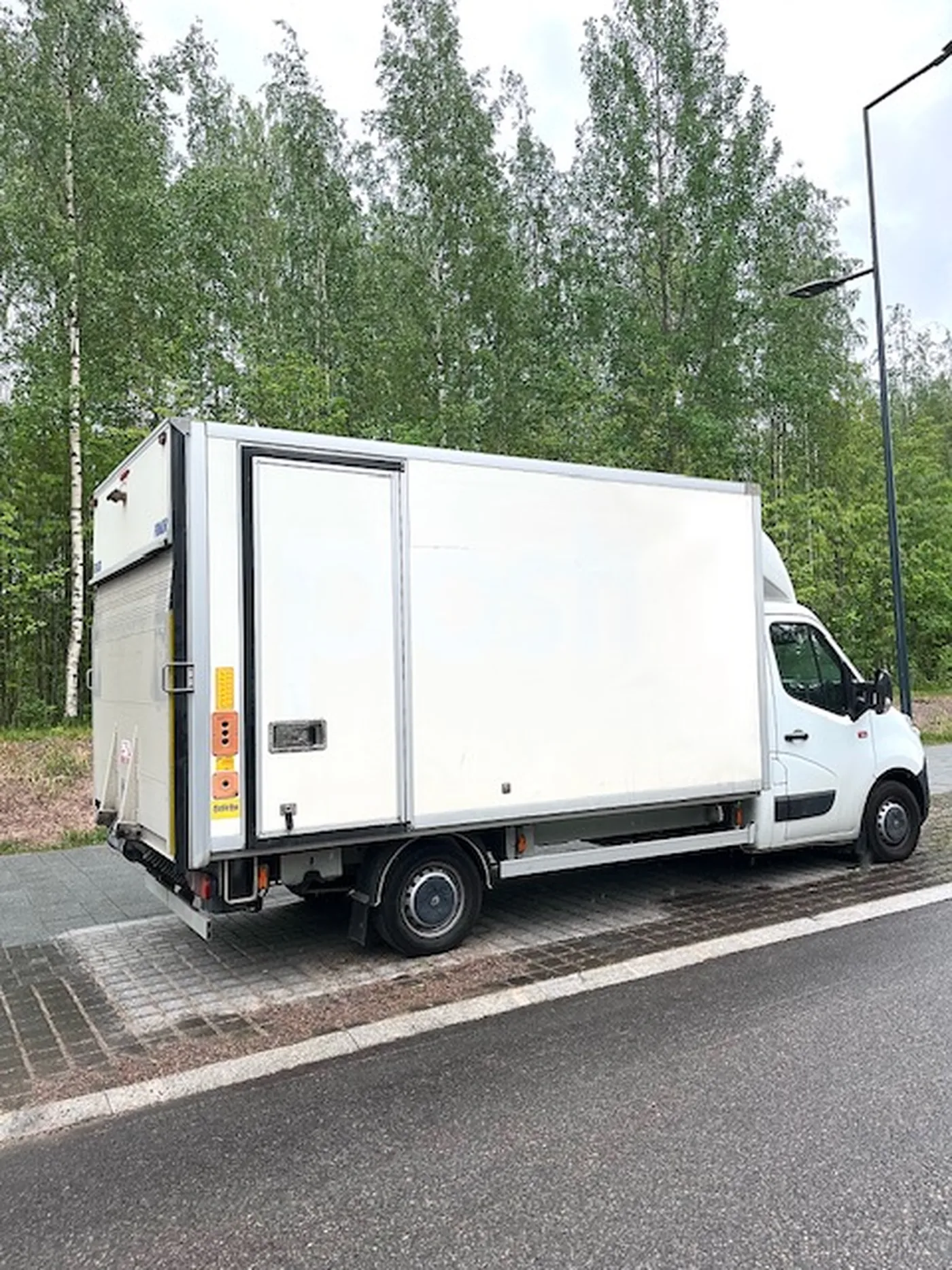 Nordicos Group Oy:n valkoinen muuttoauto pysäköitynä koivikon reunaan